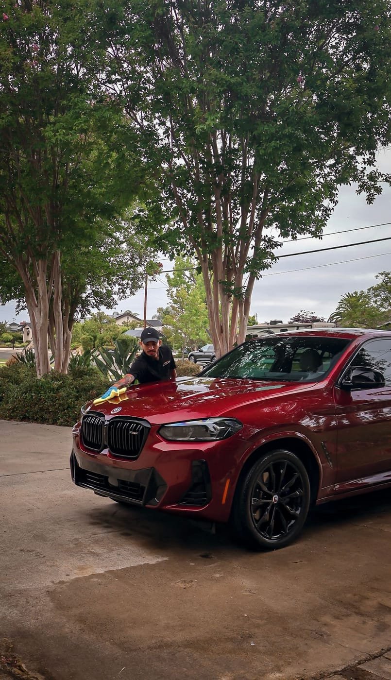 Joji's Mobile Detailing technician wiping down a red BMW in La Mesa, CA