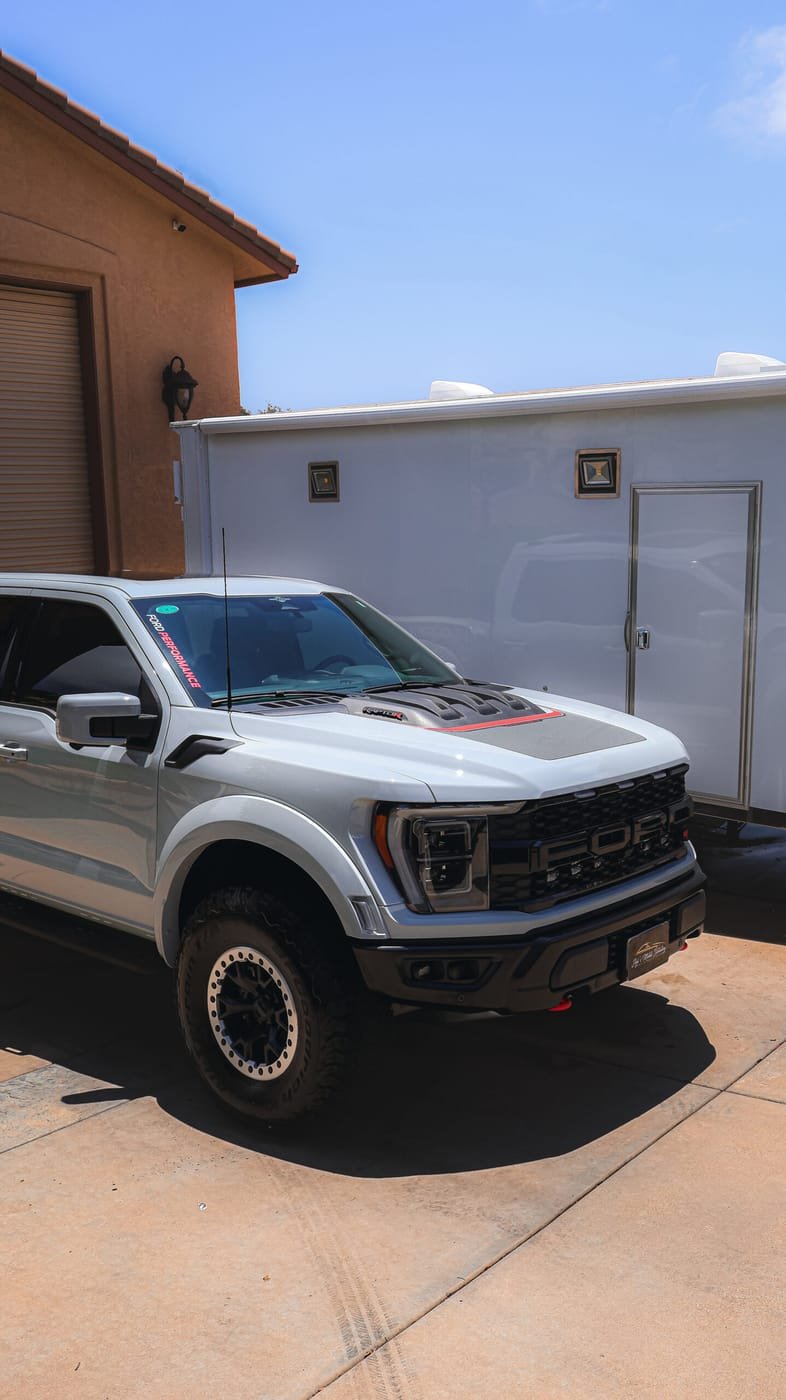 Ford Raptor with black plastic bumper and fender trim, detailed in a San Diego driveway