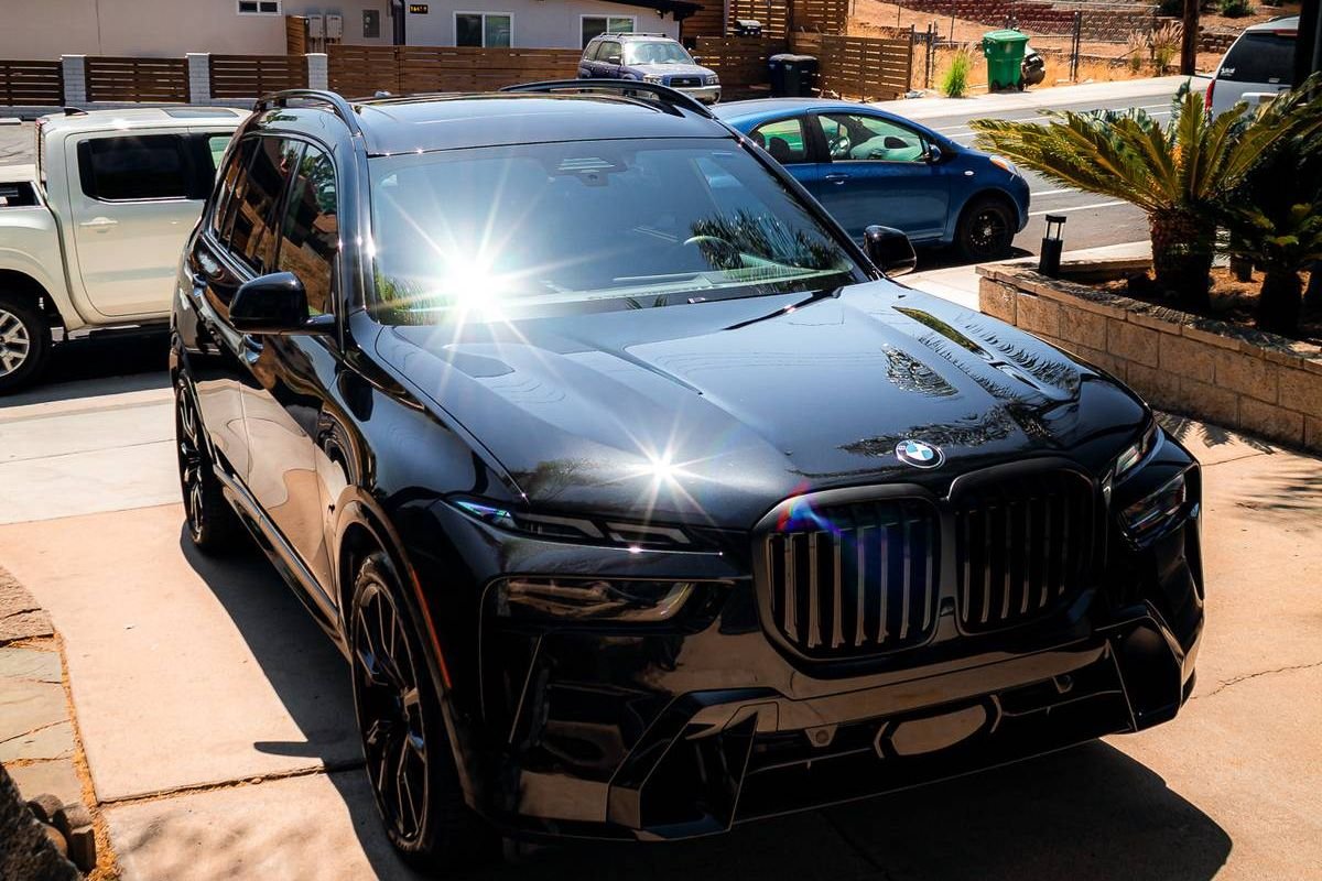 Glossy black BMW X7 reflecting the sun, the deep, clear finish paint correction is meant to bring back