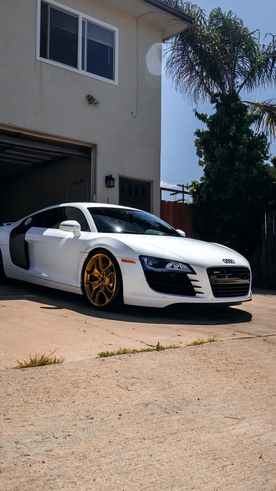Glossy white Audi R8 parked in front of a garage