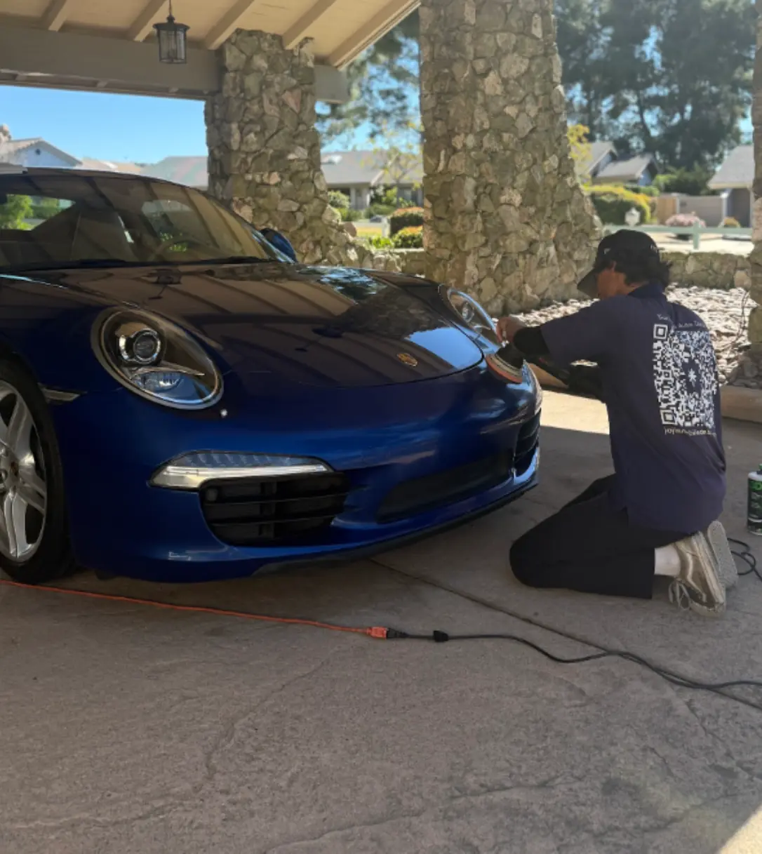 Alpine paint correction: technician machine-polishing the front bumper of a blue Porsche 911