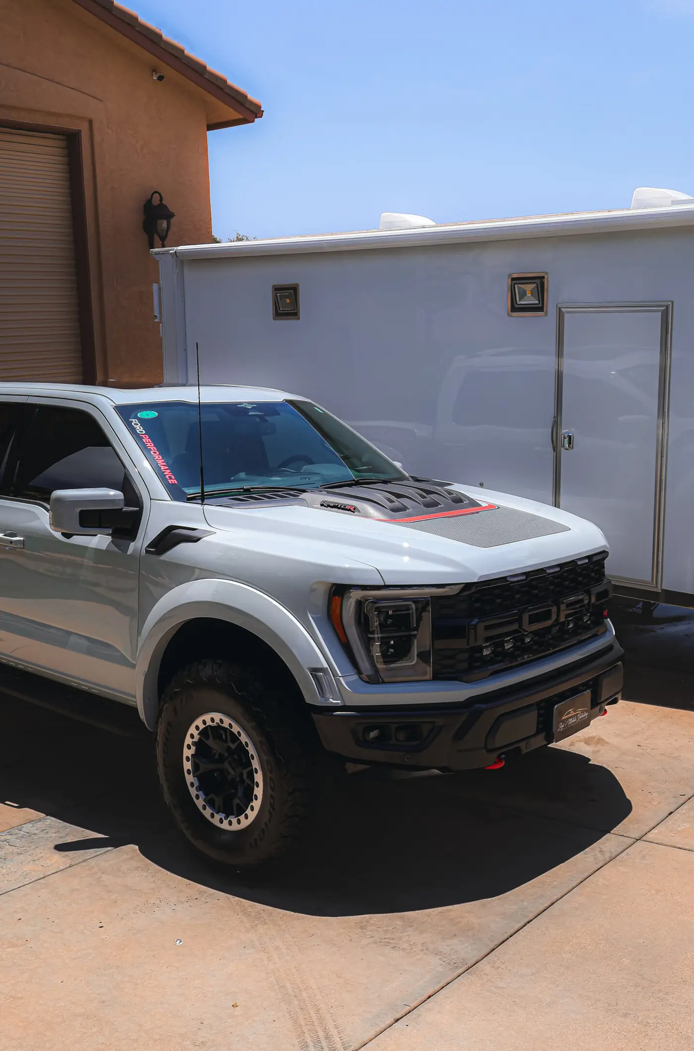 Lakeside paint correction: detailed Ford Raptor pickup parked beside a garage