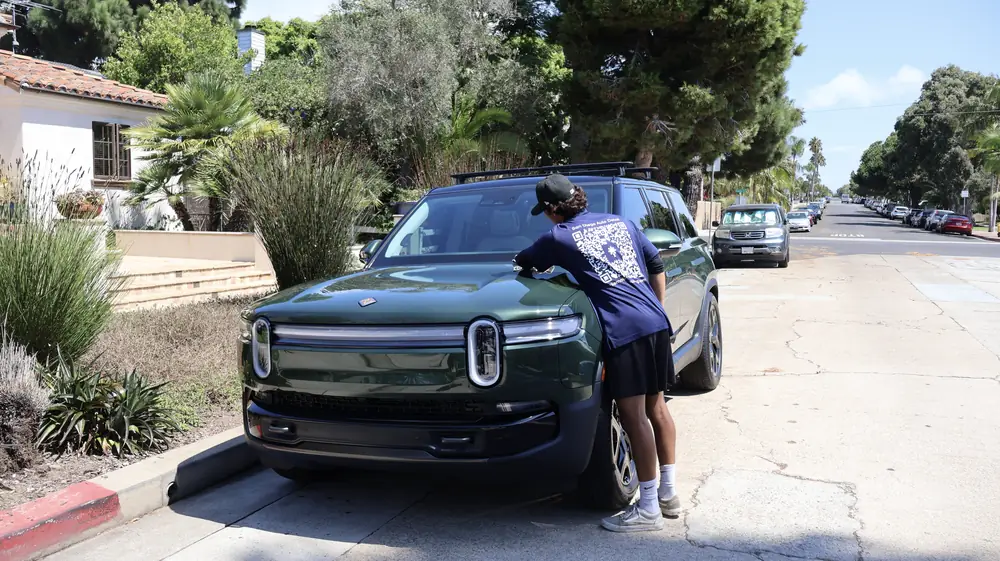 Point Loma paint correction: technician wiping down a green Rivian R1S on a residential street